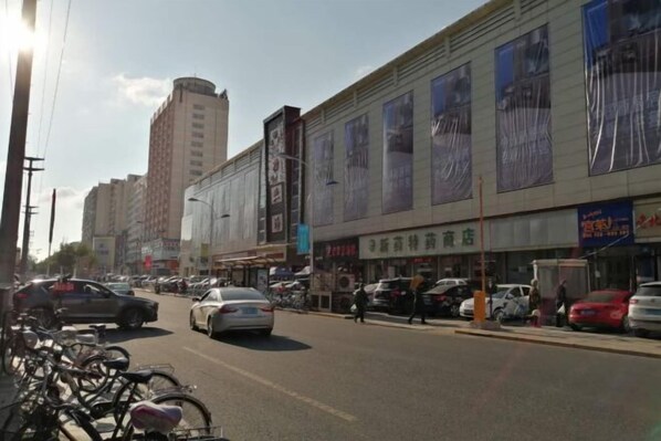 Vista de la calle con coches estacionados, bicicletas y edificios con letreros.