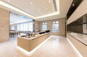 Una cocina moderna con una isla central, ventanas amplias y un área de comedor visible al fondo.