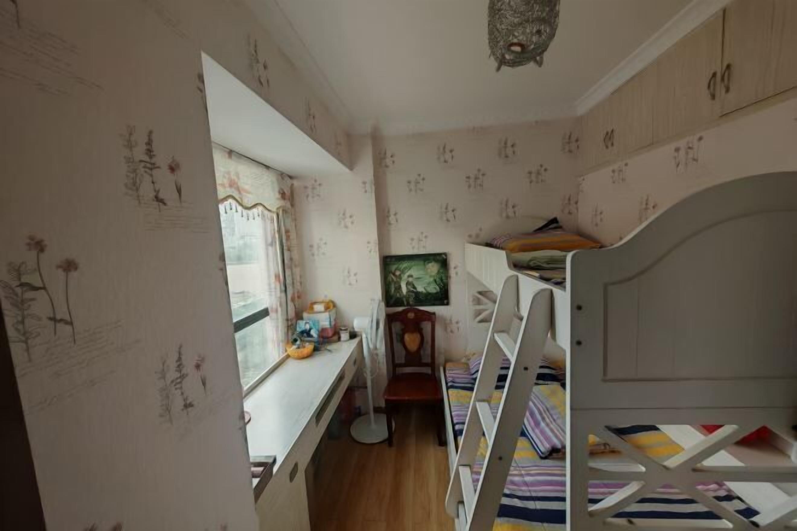 A child's bedroom with bunk beds, a desk, and a window.