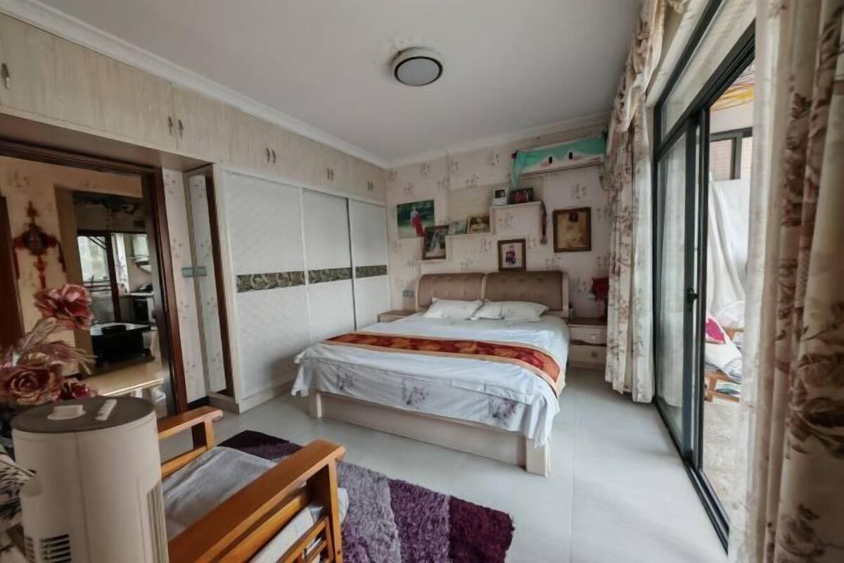 Un dormitorio con cama, armario, escritorio y ventana con cortinas.