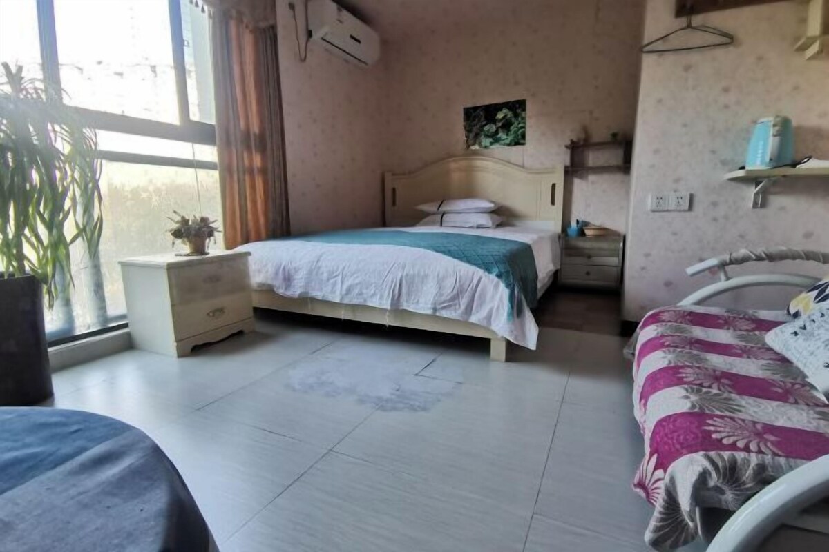 A bedroom with a bed, bedside table, and a window.