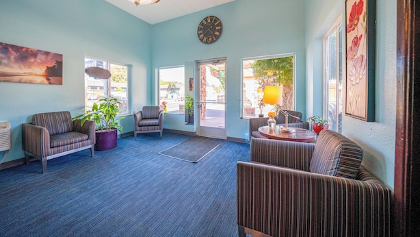 A lobby with striped sofas, a clock, and a large window. - Unicorn Inn by OYO Portland (Portland)