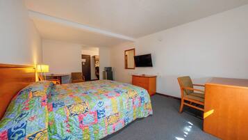 Une chambre d’hôtel avec un lit, un bureau, une chaise, une télévision et un miroir.