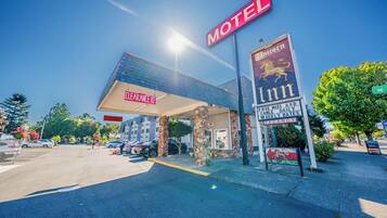 A motel with a clear sign, a covered parking area, and a stone facade.