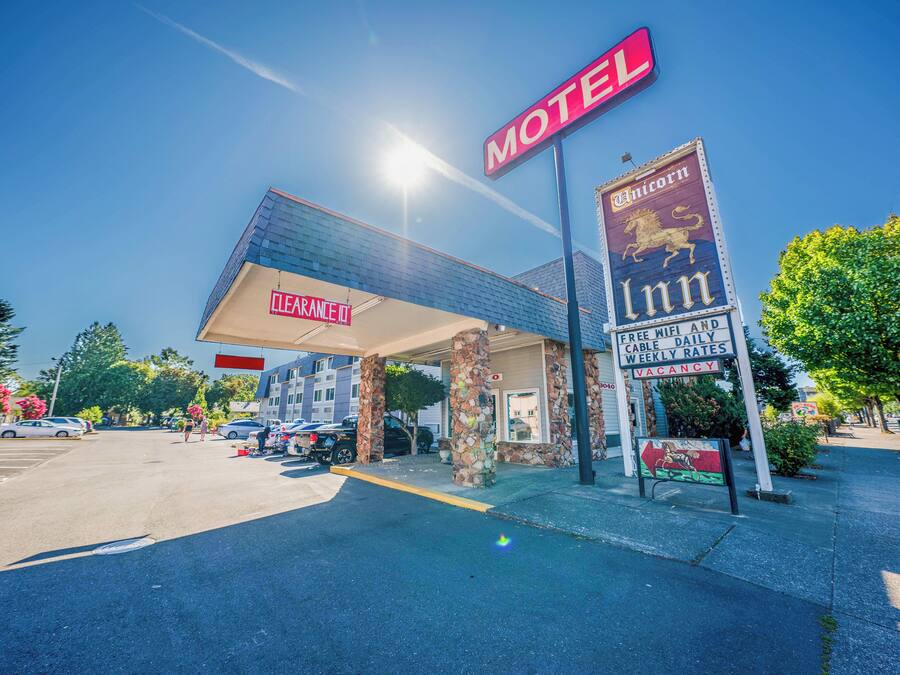 A motel with a clear sign, a covered parking area, and a stone facade.