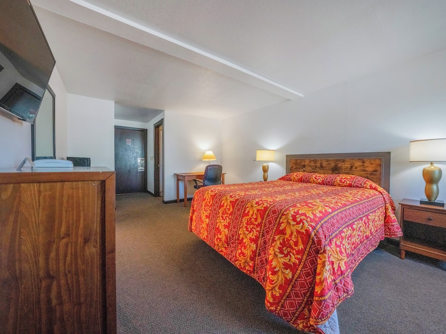Une chambre d’hôtel avec un grand lit, un bureau, une chaise et une table de chevet.