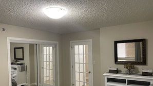 Un dormitorio con cama, cómoda, espejo y puerta que da a un baño.