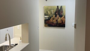 Una cocina moderna con encimera blanca, pileta de acero inoxidable y un cuadro en la pared.