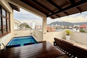 A rooftop terrace with a swimming pool, wooden furniture, and a view of the cityscape. - Salomone (Florianópolis)