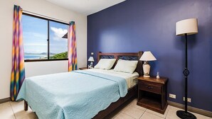A bedroom with a bed, nightstands, a lamp, and a view of the outdoors. - Ocean View 2Br/2Bth Condo In Tamarindo (Tamarindo)