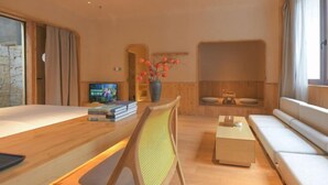 A modern living room with a wooden coffee table, a sofa, and a television. - Lugu Lake Mosuo Home Hotel (Yanyuan)