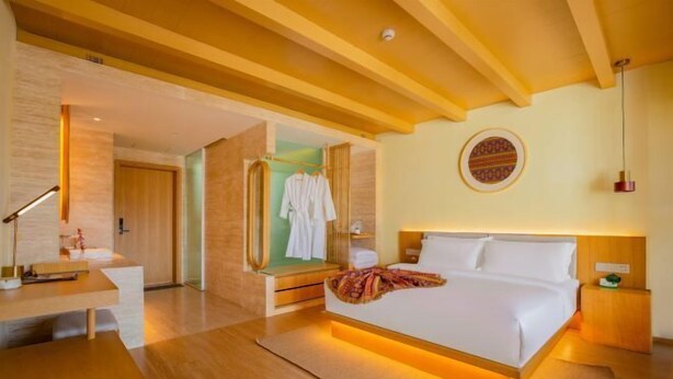 Una habitación de hotel moderna con una cama grande, un escritorio y un espejo.