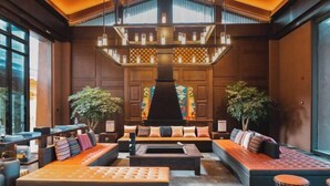 A spacious lobby with a central seating area, a fireplace, and large windows. - Lugu Lake Mosuo Home Hotel (Yanyuan)