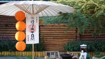 Entorno tradicional japonés con estructura de madera, un paraguas y faroles.