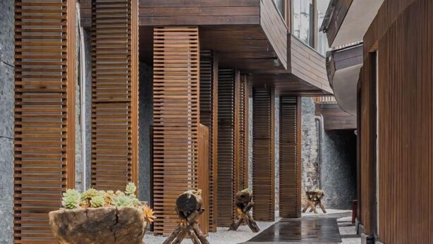 A modern building with wooden slatted walls, a wet floor, and a wooden planter with succulents. - Lugu Lake Mosuo Home Hotel (Yanyuan)