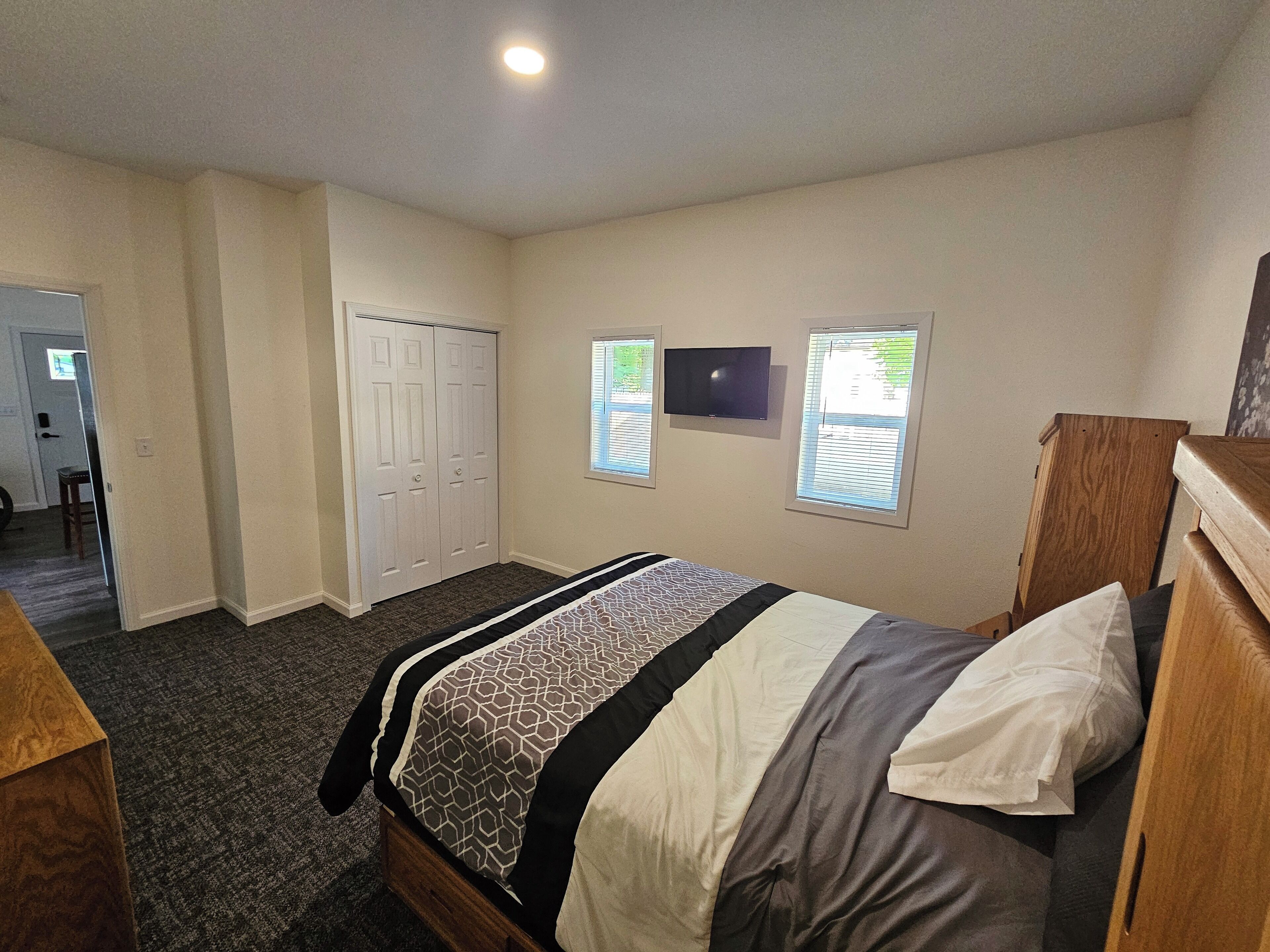 Une chambre à coucher avec un lit, une armoire, une télévision et une fenêtre.