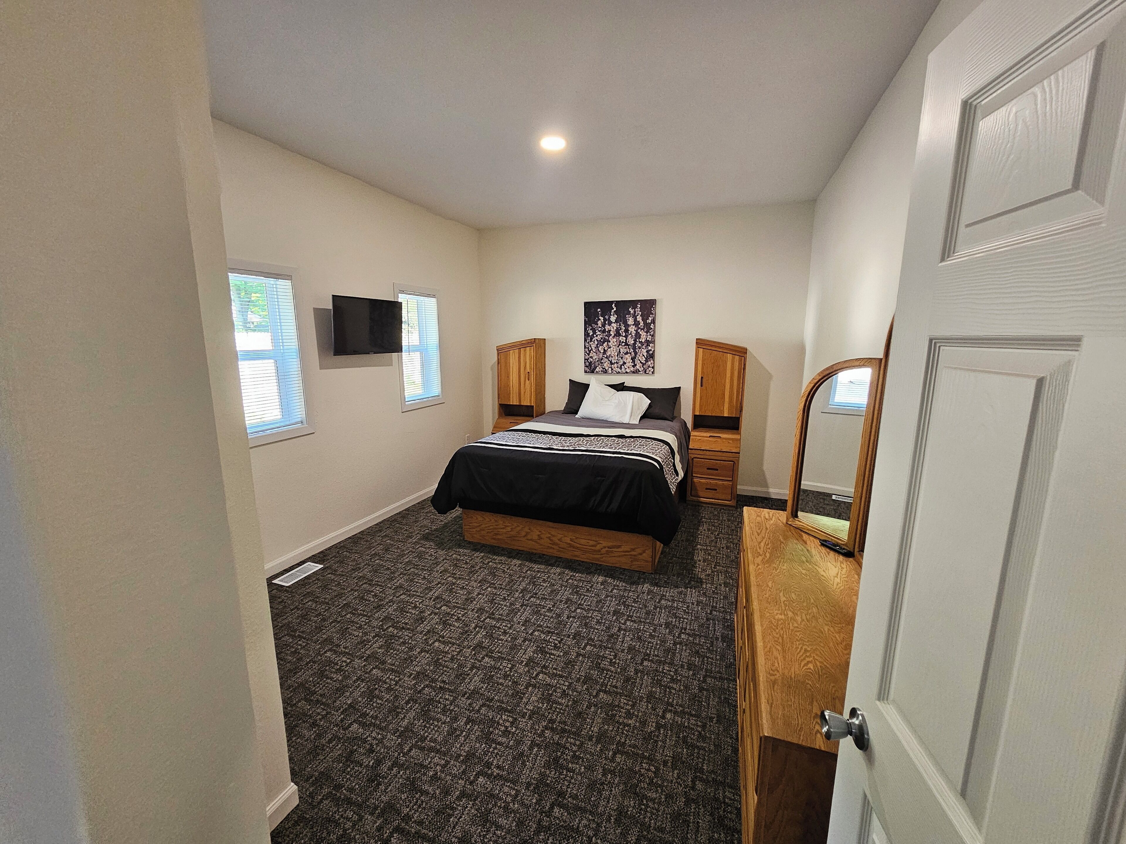 Une chambre à coucher avec un lit, une télévision, un miroir et une fenêtre.