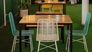 A cozy indoor seating area with a wooden table and chairs, surrounded by green artificial grass, and adorned with string lights. - Hotel Plataneras Plaza (Apartadó)