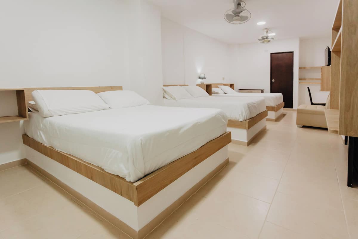 A modern bedroom with two beds, a wooden headboard, a bedside table with a lamp, and a built-in TV shelf.