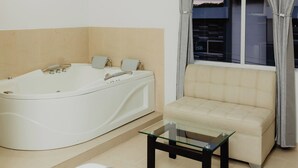 A modern bathroom with a freestanding bathtub, a beige sofa, and a glass coffee table. - Hotel Plataneras Plaza (Apartadó)