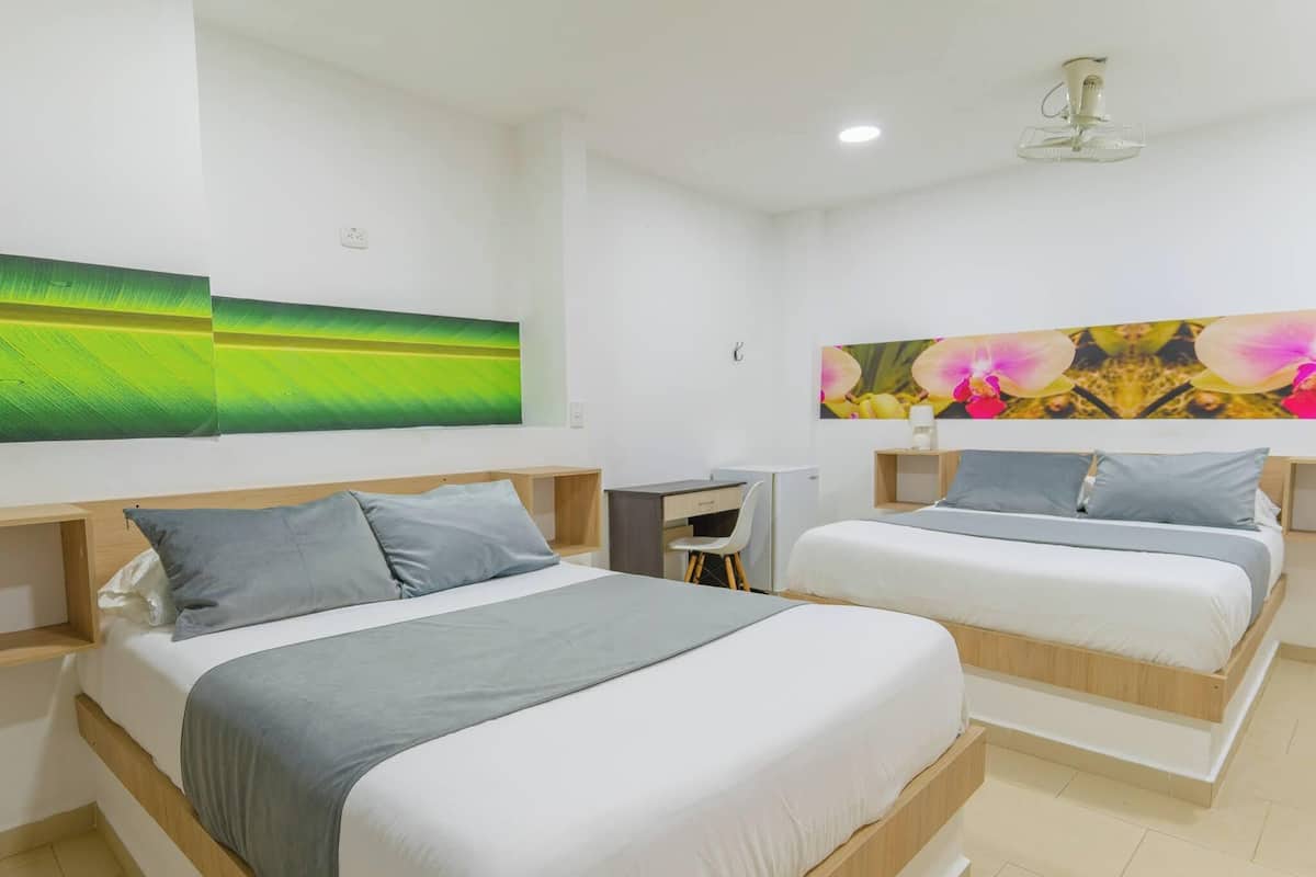 A hotel room with two beds, a desk, and a chair.