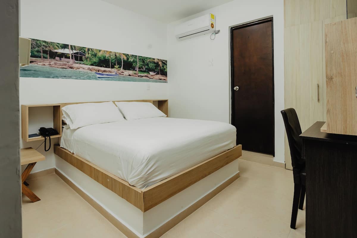 A bedroom with a wooden bed, a desk, a chair, and a door.