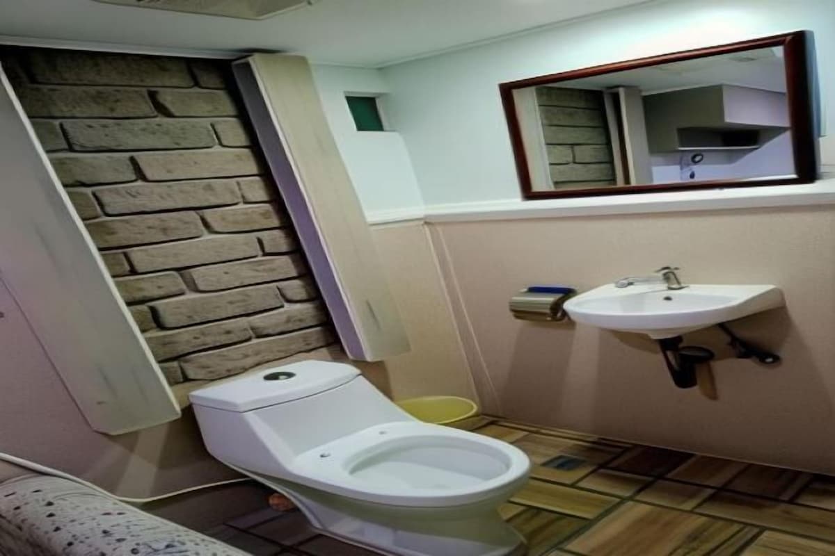 A bathroom with a toilet, sink, and a mirror.