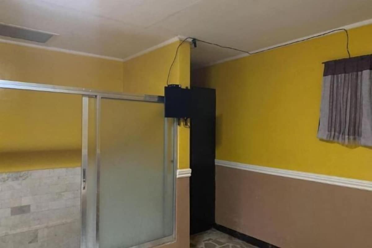 A room with yellow walls, a glass door, a black speaker, and a curtain.