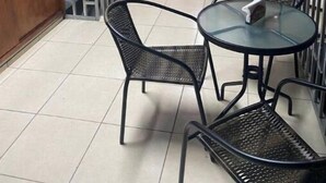 A small, enclosed dining area with a round glass table and two chairs, a wooden counter, and a television mounted on the wall. - Apartamentos Yusem #3

 (Alajuela)
