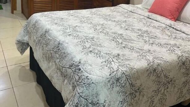 A bedroom with a bed, a wooden wardrobe, a nightstand, and a wall-mounted air conditioner. - Apartamentos Yusem #3

 (Alajuela)