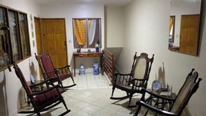 A room with a tiled floor, wooden rocking chairs, a desk with a chair, and a window with curtains. - Apartamentos Yusem #3

 (Alajuela)