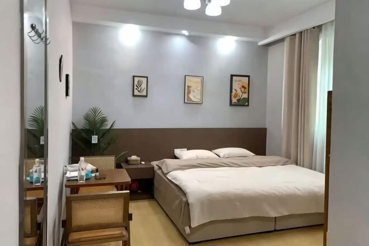 Ein Hotelzimmer mit Bett, Nachttisch, Lampe und Wandbildern.