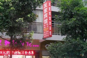 Un edificio con un letrero rojo y un árbol en primer plano.