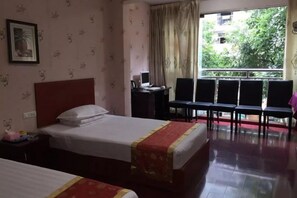 Habitación de hotel con dos camas, un escritorio y vista a zonas verdes.