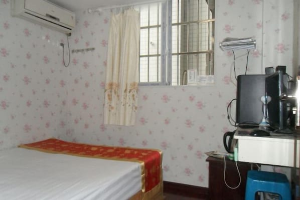 A room with a bed, a desk with a computer, an air conditioner, and a window with curtains. - Wulong Youjia Hotel (Chongqing)