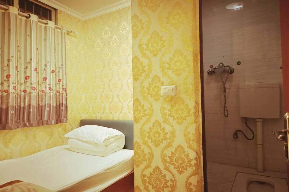 Ein kleines Zimmer mit einem Einzelbett und einer Dusche.