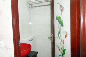 A bathroom with a shower, toilet, and a red basin.