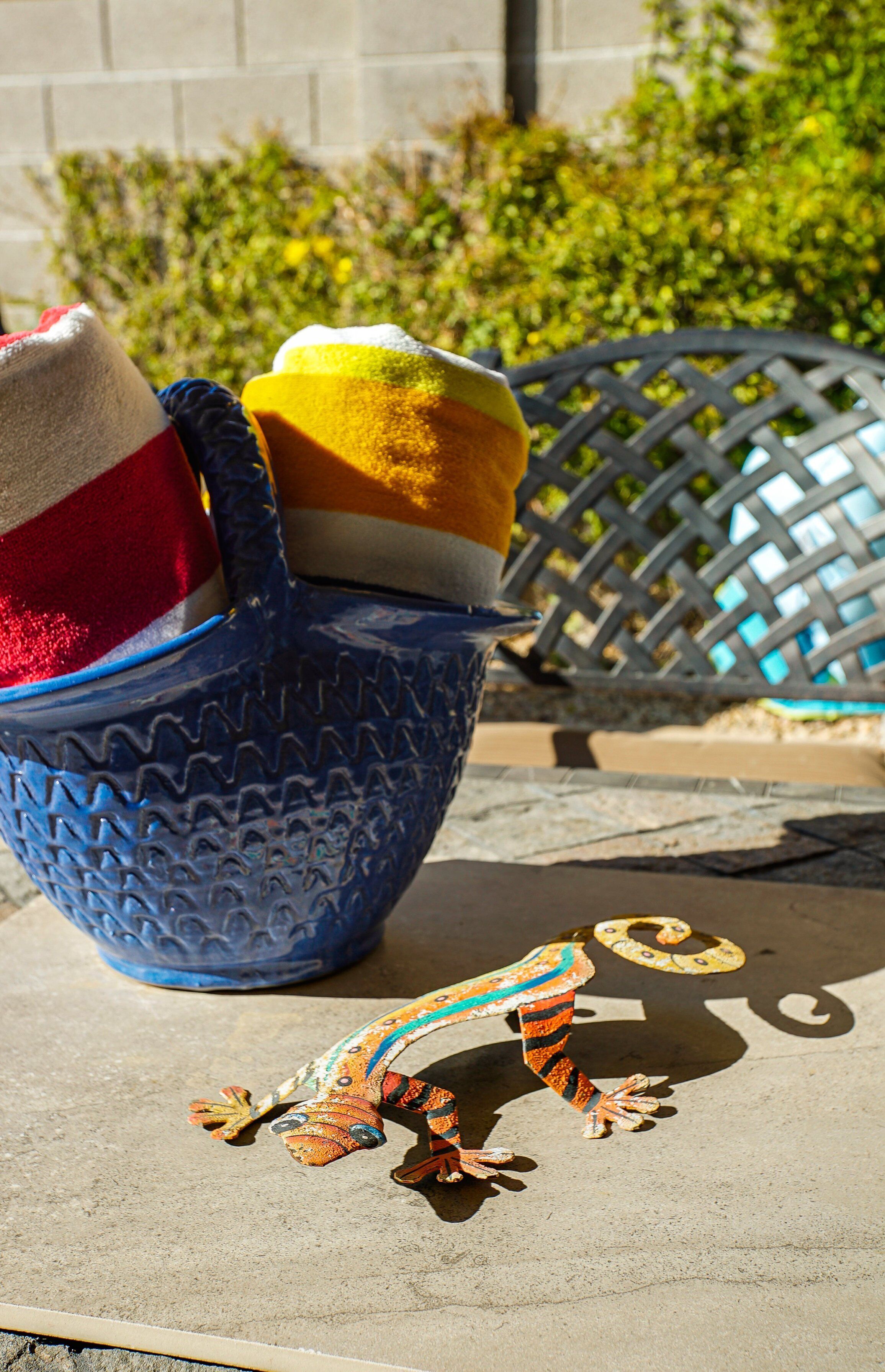 A blue woven basket with a colorful lizard figurine on a concrete surface.