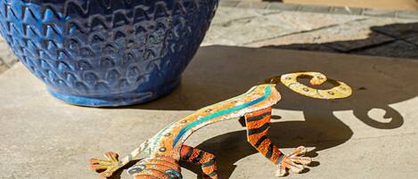 A blue woven basket with a colorful lizard figurine on a concrete surface.