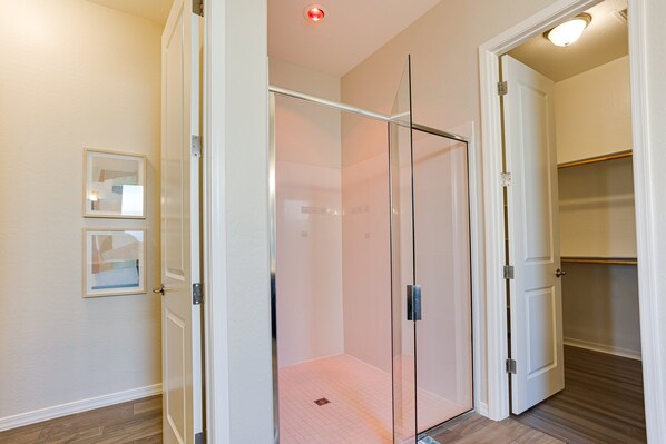 Um closet espaçoso com porta de vidro, um quadro na parede e piso de madeira.