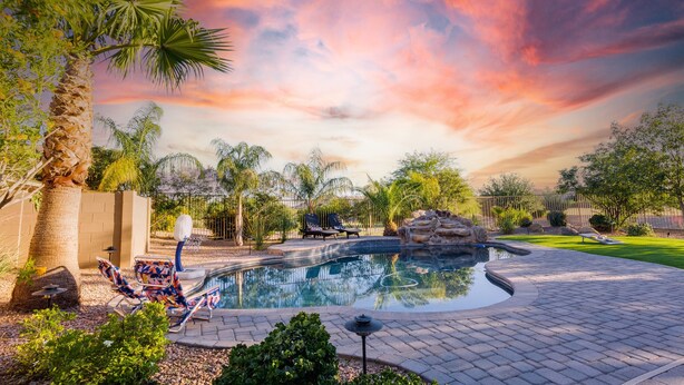 A swimming pool with lounge chairs, palm trees, and a sunset sky. - Creekside Queen Creek (Queen Creek)