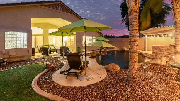 A backyard with a swimming pool, outdoor seating, and a well-maintained garden. - 165th Goodyear (Goodyear)