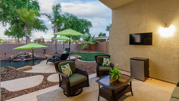 An outdoor patio area with wicker furniture, a small pool, and a TV mounted on the wall. - 165th Goodyear (Goodyear)