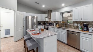 A modern kitchen with white cabinets, stainless steel appliances, and a granite countertop. - 165th Goodyear (Goodyear)