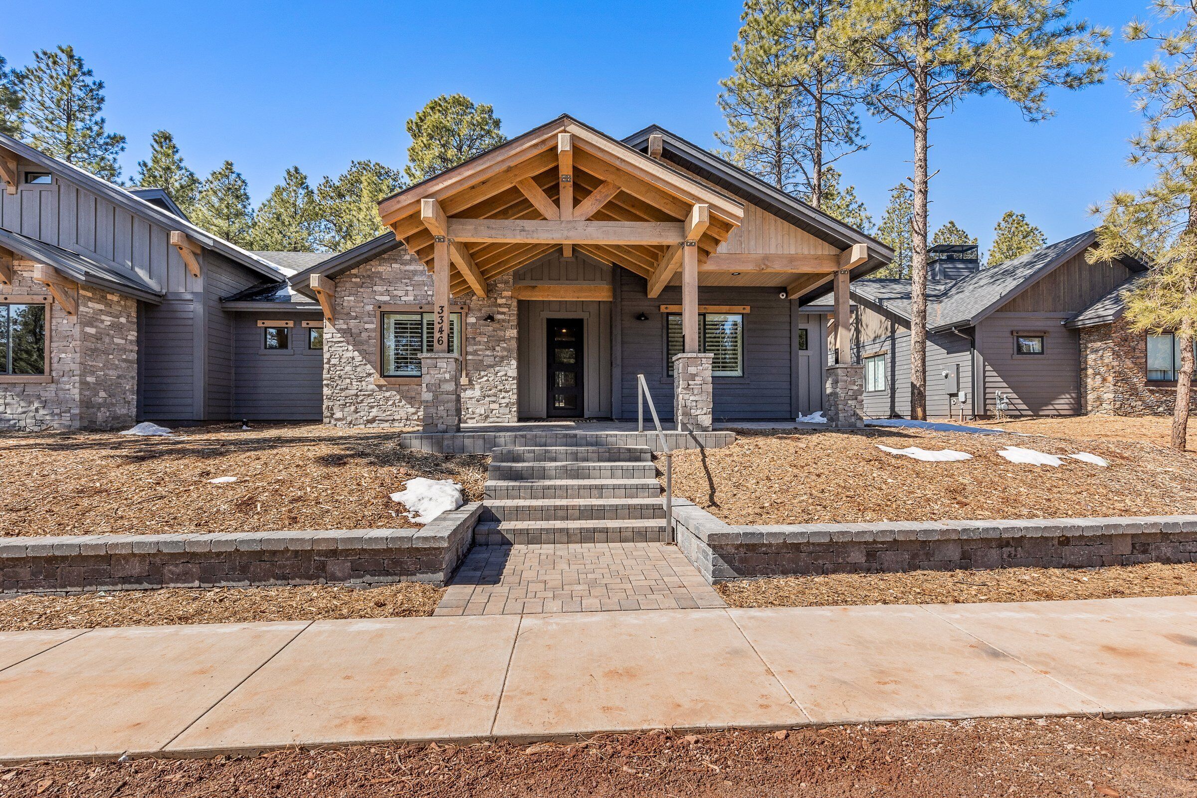 A modern two-story house with a stone facade, a covered front porch, and a well-maintained front yard.