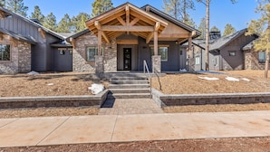 A modern two-story house with a stone facade, a covered front porch, and a well-maintained front yard.