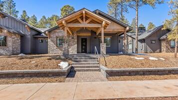 A modern two-story house with a stone facade, a covered front porch, and a well-maintained front yard.