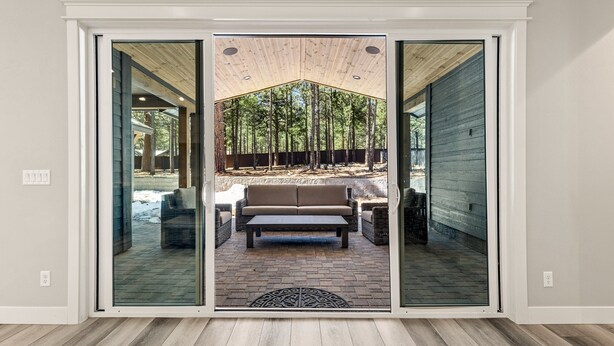 A sliding glass door leading to an outdoor patio with a wooden ceiling, a bench, and a sofa.