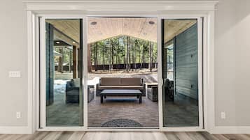 A sliding glass door leading to an outdoor patio with a wooden ceiling, a bench, and a sofa.