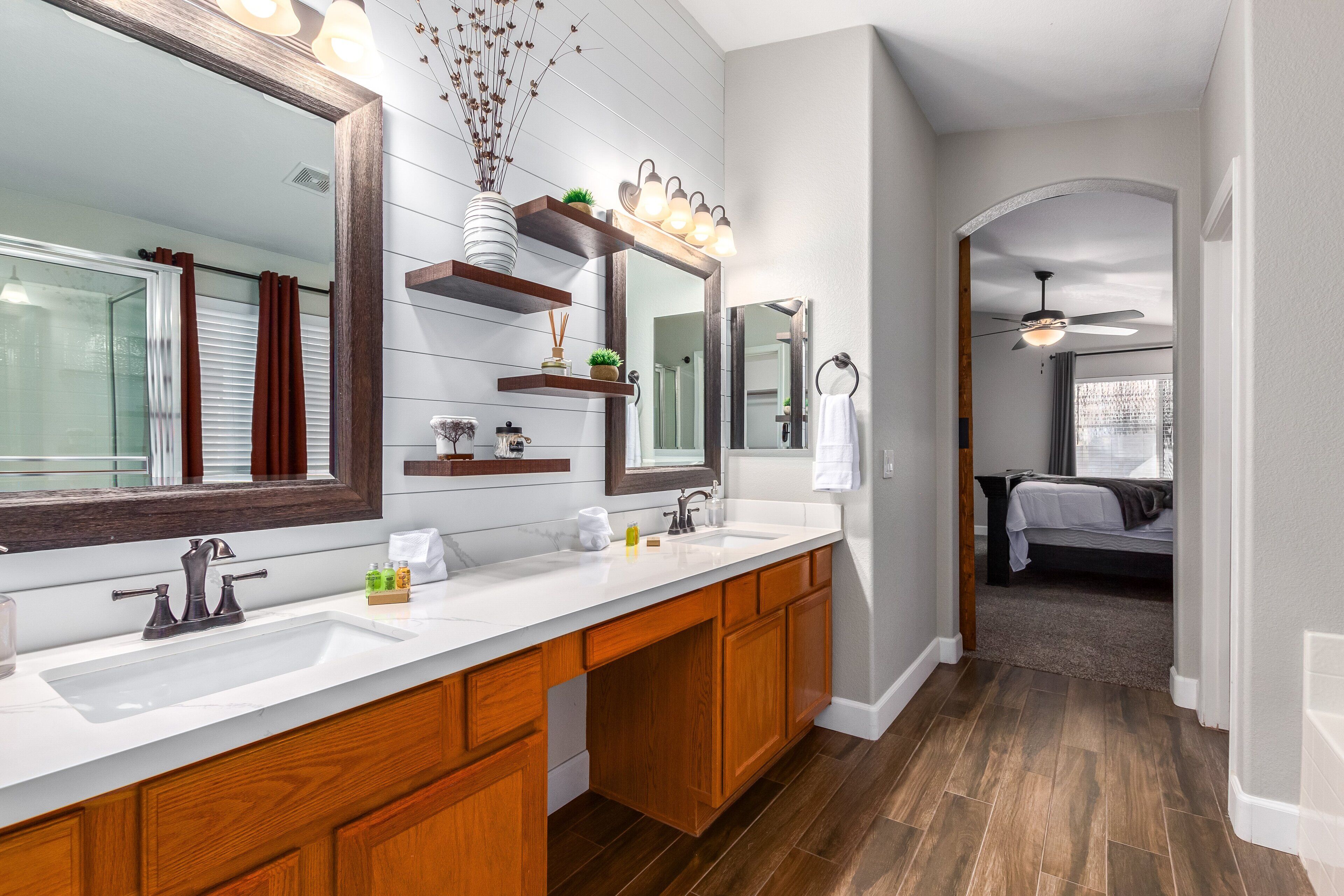Une salle de bain moderne avec un grand miroir, des meubles en bois et un plan de travail blanc.